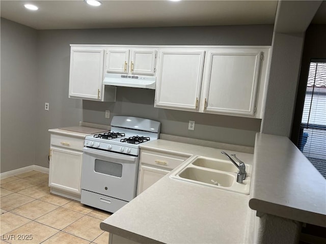 kitchen with under cabinet range hood, white gas range, light countertops, and a sink