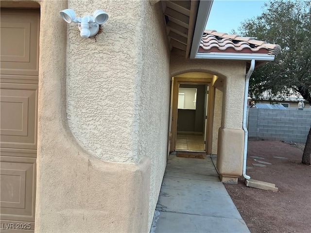 view of exterior entry featuring a tile roof and stucco siding