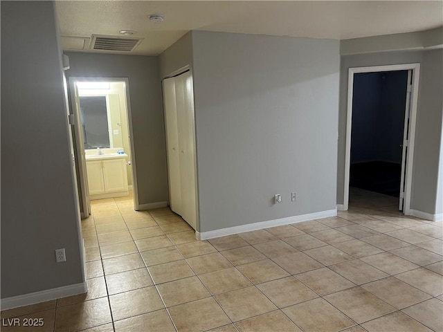 unfurnished room featuring light tile patterned flooring, a sink, visible vents, and baseboards