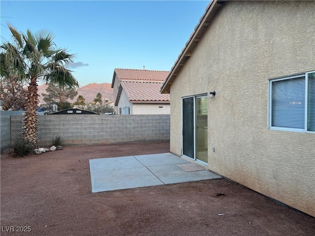 exterior space with fence, a mountain view, and a patio