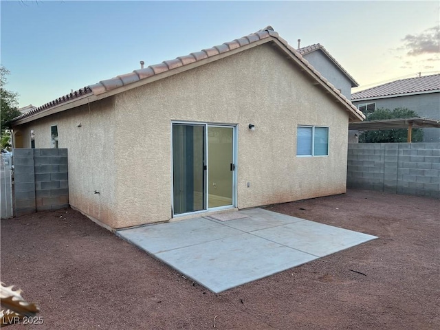 back of property with a tile roof, a patio area, fence, and stucco siding