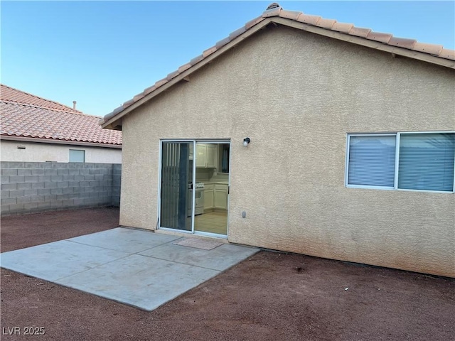 back of house featuring a patio area, fence, a tile roof, and stucco siding