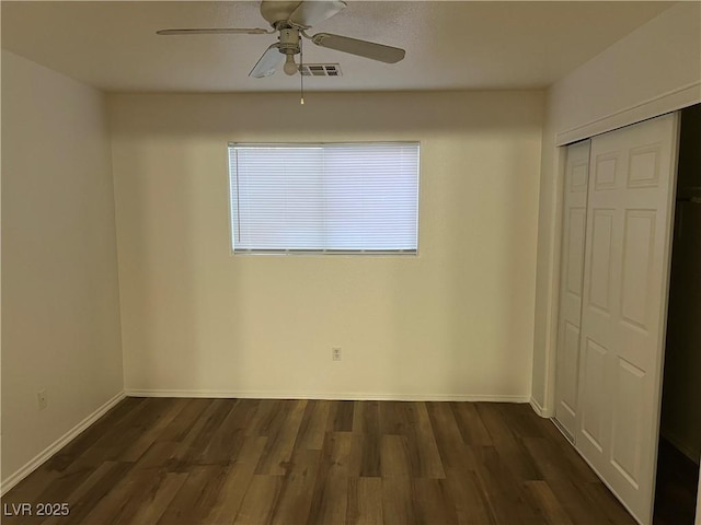 unfurnished bedroom featuring baseboards, a closet, visible vents, and dark wood-style flooring