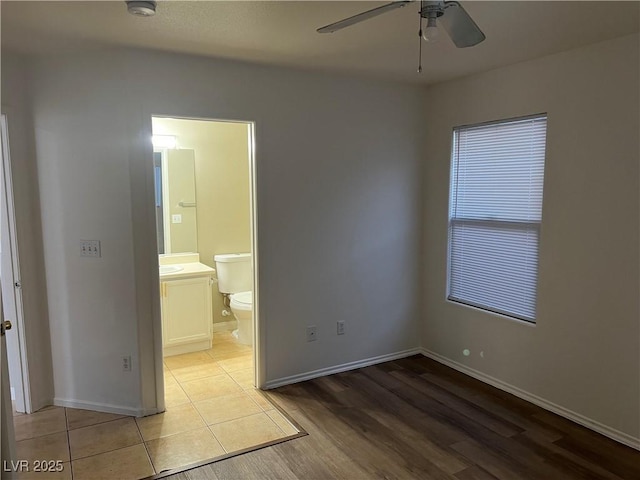 unfurnished bedroom with light wood finished floors, connected bathroom, and baseboards