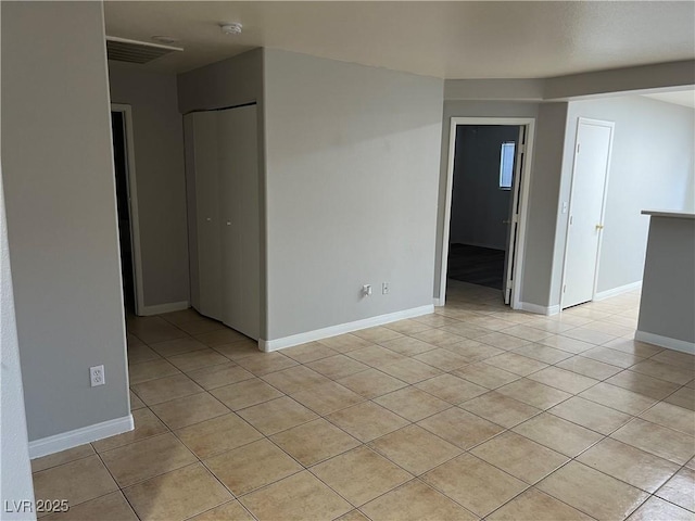 spare room featuring light tile patterned floors, visible vents, and baseboards