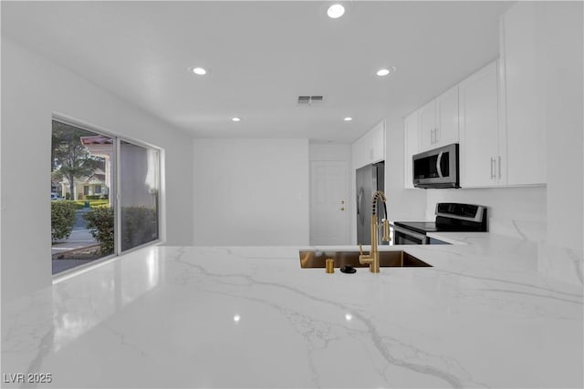 kitchen with light stone counters, recessed lighting, visible vents, white cabinets, and appliances with stainless steel finishes