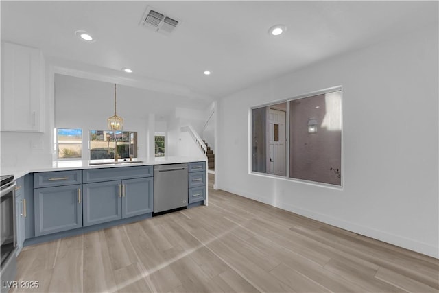 kitchen with light countertops, visible vents, a sink, dishwasher, and a peninsula