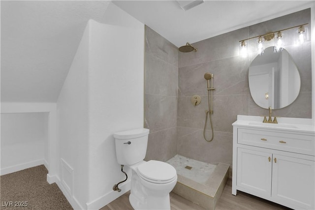 full bath with baseboards, tiled shower, vanity, and toilet