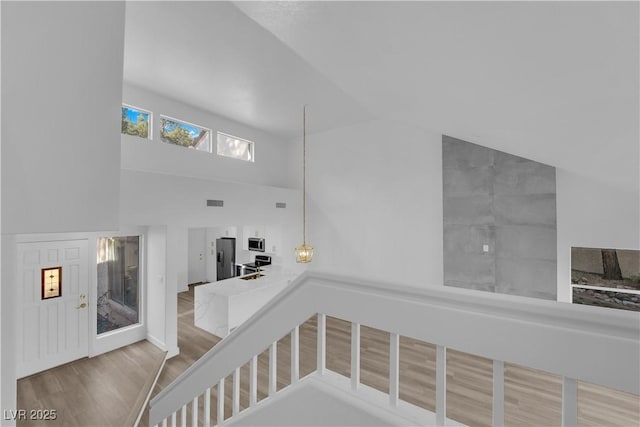 stairway featuring visible vents, high vaulted ceiling, and wood finished floors