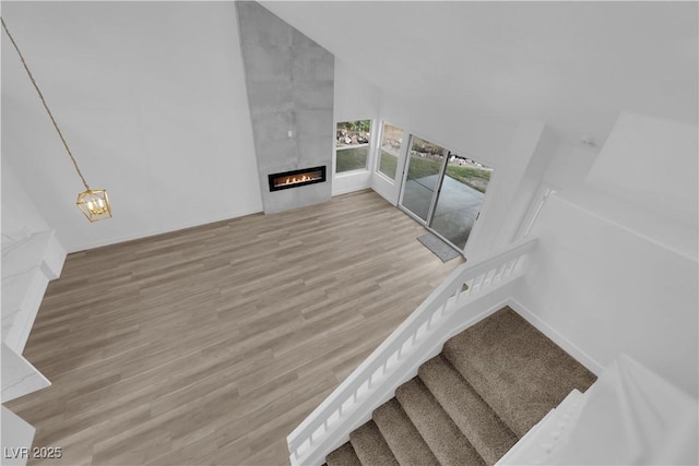 stairway featuring a tiled fireplace, wood finished floors, and a notable chandelier