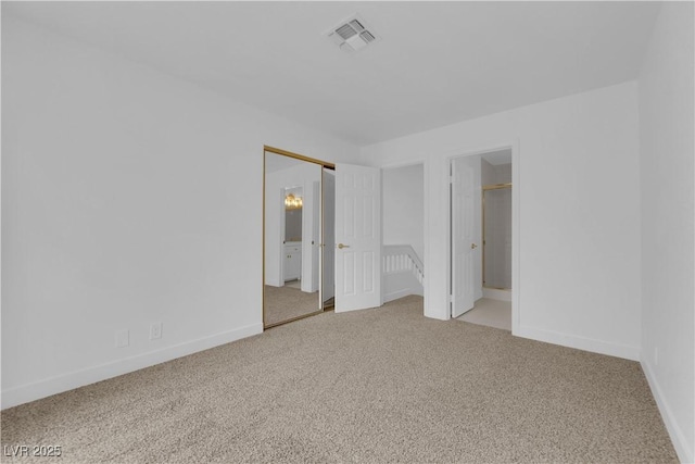 unfurnished bedroom featuring baseboards, ensuite bathroom, visible vents, and light colored carpet