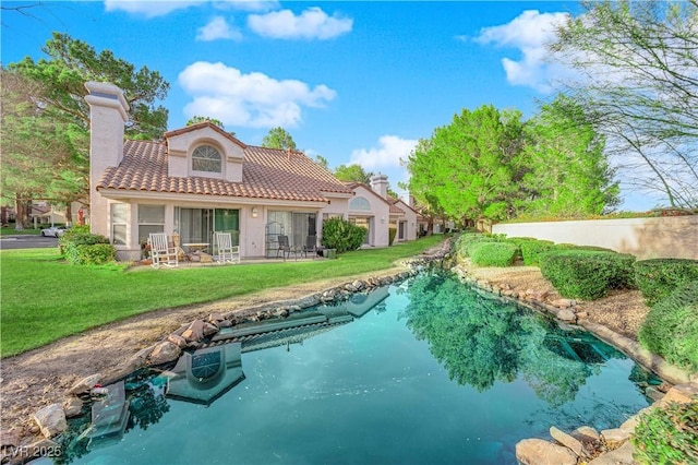 back of property with stucco siding, a tiled roof, a chimney, and a yard