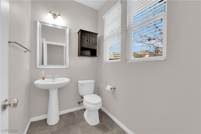 half bath featuring toilet and baseboards