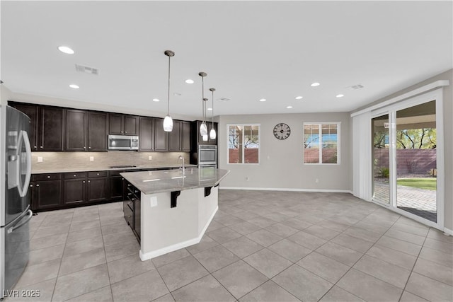 kitchen featuring light tile patterned floors, tasteful backsplash, visible vents, appliances with stainless steel finishes, and a sink