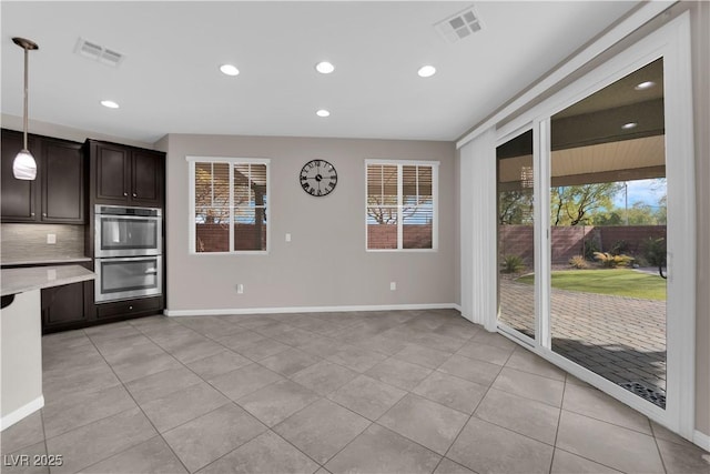 kitchen with tasteful backsplash, stainless steel double oven, visible vents, and dark brown cabinetry