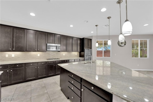 kitchen featuring stainless steel appliances, visible vents, decorative backsplash, light tile patterned flooring, and a sink