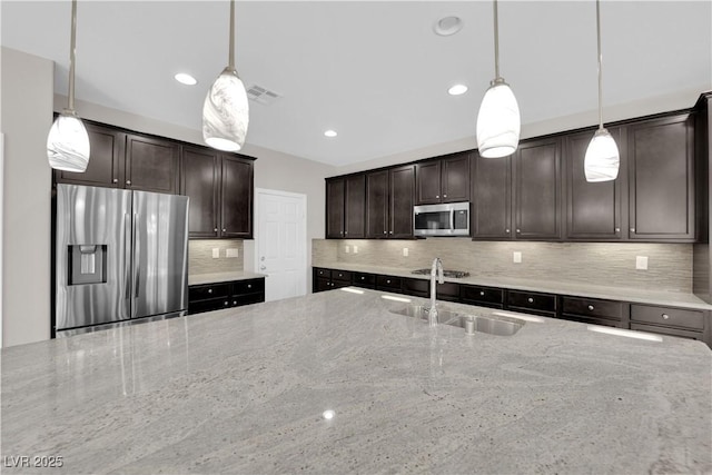 kitchen featuring light stone counters, stainless steel appliances, tasteful backsplash, a sink, and dark brown cabinetry