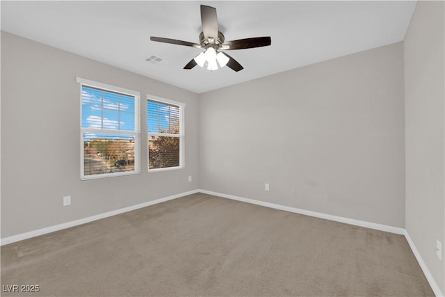 carpeted spare room with ceiling fan, visible vents, and baseboards