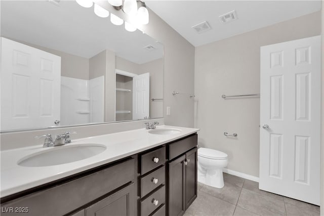 bathroom featuring toilet, tile patterned flooring, double vanity, and a sink