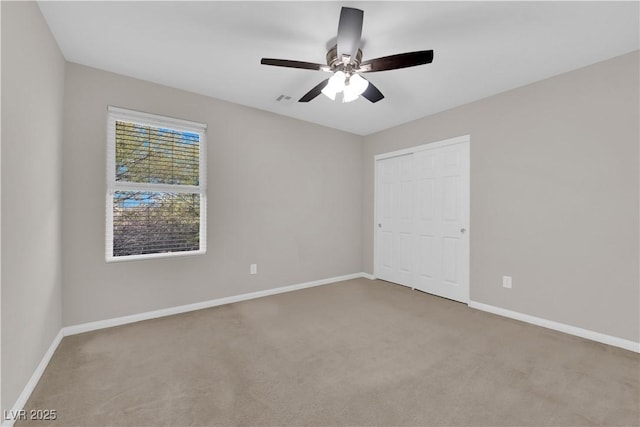 unfurnished bedroom with carpet, baseboards, ceiling fan, and a closet