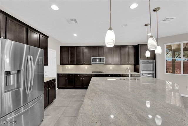 kitchen featuring light tile patterned floors, stainless steel appliances, visible vents, decorative backsplash, and a sink