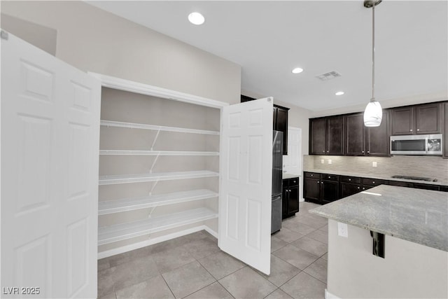 kitchen with light tile patterned floors, visible vents, light stone countertops, stainless steel appliances, and backsplash