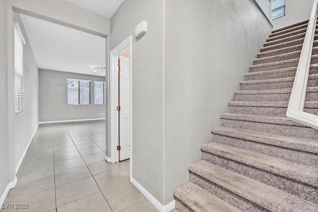 stairway with baseboards and tile patterned floors