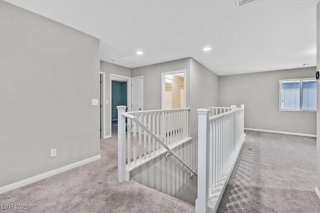 hall featuring carpet floors, baseboards, and an upstairs landing