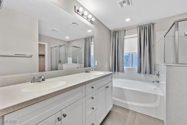 bathroom featuring visible vents, a sink, a shower stall, and tile patterned floors