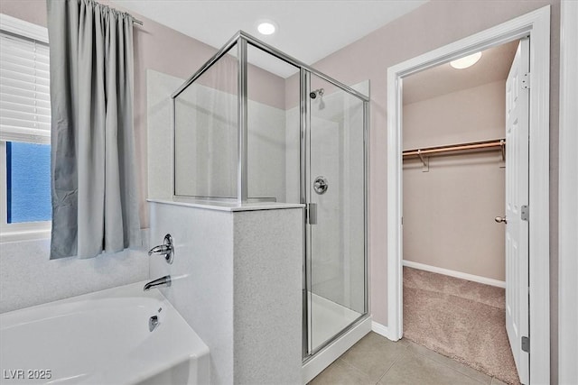 full bathroom featuring baseboards, a spacious closet, a shower stall, a bath, and tile patterned floors