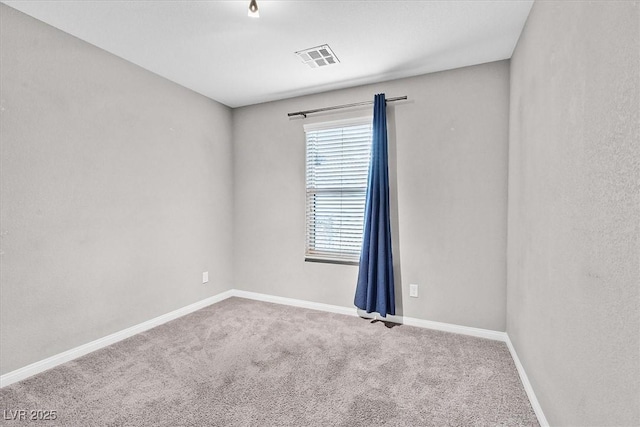 spare room featuring carpet floors, visible vents, and baseboards