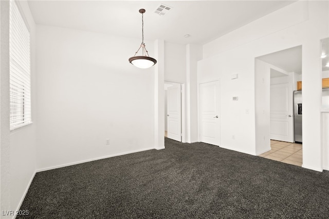 carpeted empty room featuring baseboards and visible vents