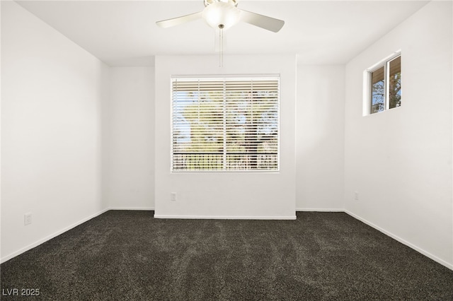 spare room featuring a wealth of natural light, dark carpet, and baseboards