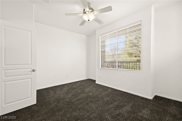 spare room featuring dark carpet, baseboards, and ceiling fan