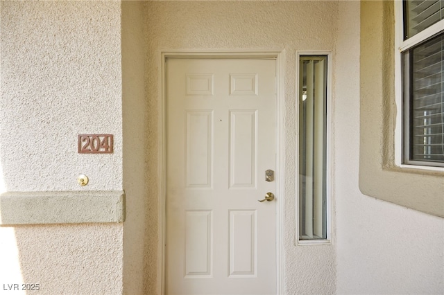 doorway to property featuring stucco siding