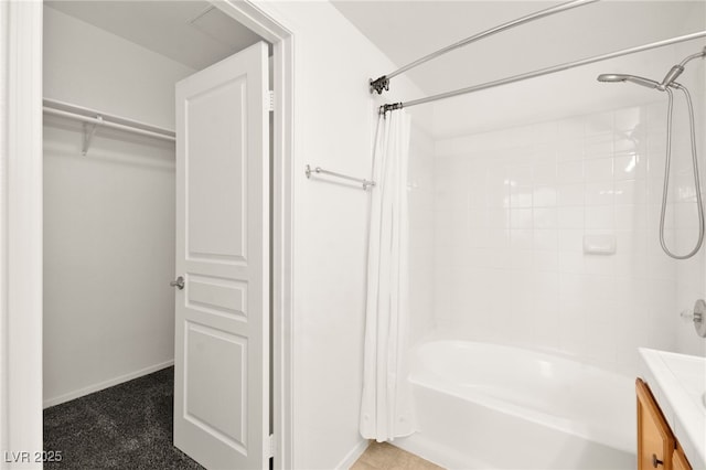 full bath featuring a walk in closet, shower / tub combo with curtain, vanity, and baseboards