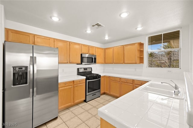 kitchen featuring light tile patterned floors, visible vents, tile countertops, appliances with stainless steel finishes, and a sink