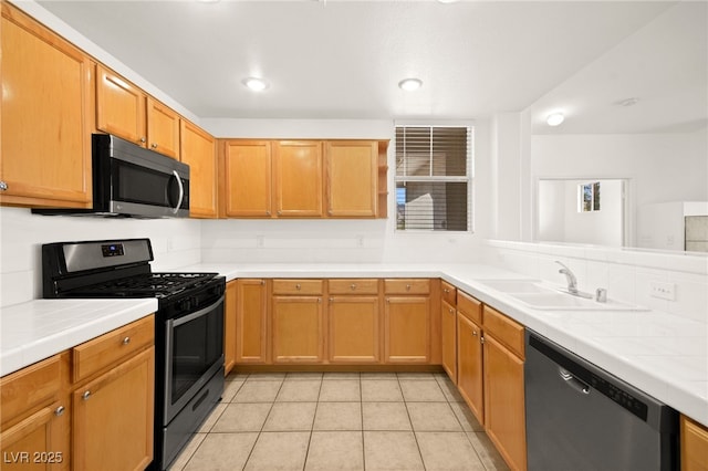 kitchen featuring appliances with stainless steel finishes, light tile patterned flooring, a sink, and tile counters