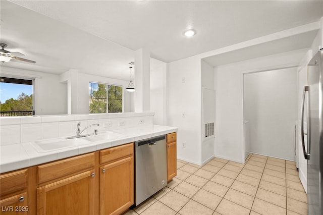 kitchen with tile counters, appliances with stainless steel finishes, light tile patterned flooring, a sink, and ceiling fan