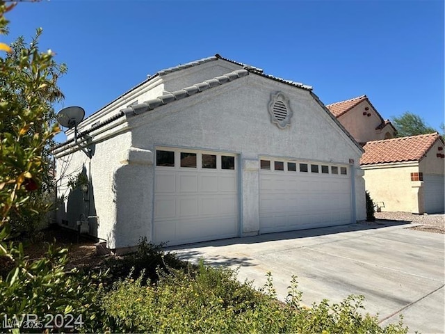 view of side of property with driveway, a tile roof, and stucco siding