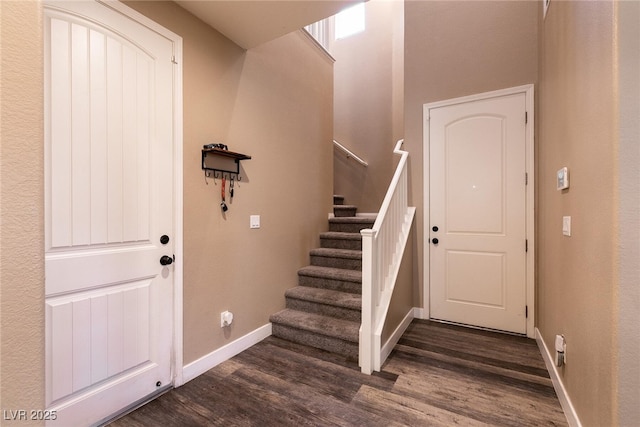 entryway with stairway, dark wood-style flooring, and baseboards