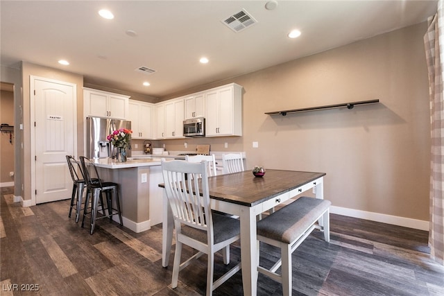 dining room with baseboards, dark wood-type flooring, visible vents, and recessed lighting