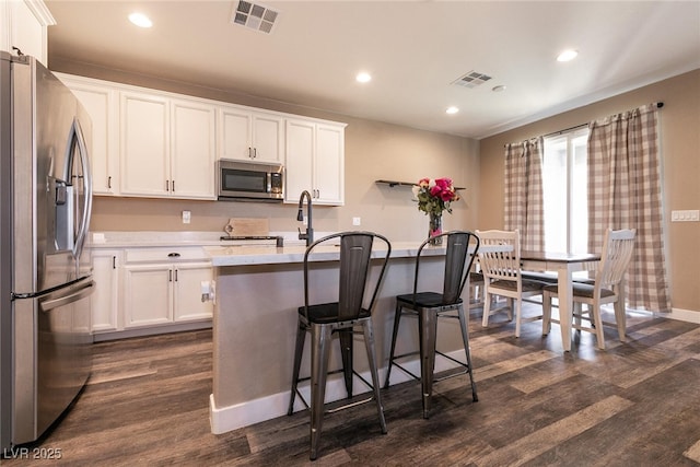 kitchen featuring white cabinets, visible vents, stainless steel appliances, and dark wood finished floors