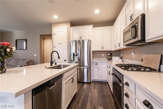 kitchen with appliances with stainless steel finishes, a kitchen island with sink, white cabinetry, and a sink