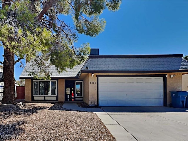 view of front of home with concrete driveway, an attached garage, and stucco siding