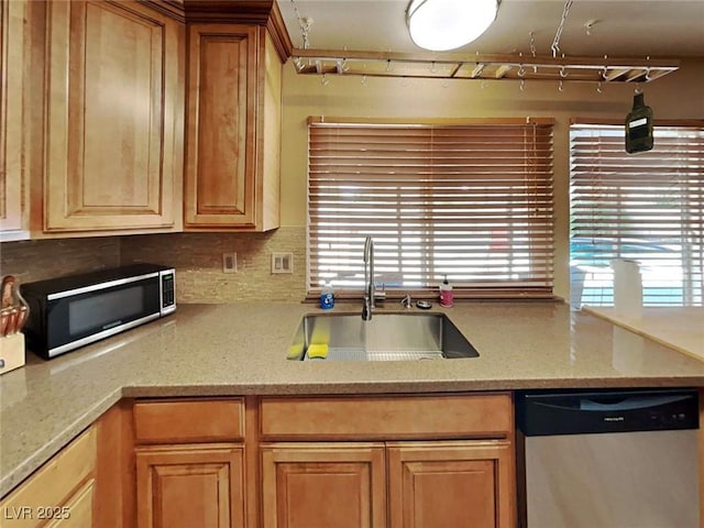 kitchen featuring appliances with stainless steel finishes, a sink, decorative backsplash, and light stone countertops