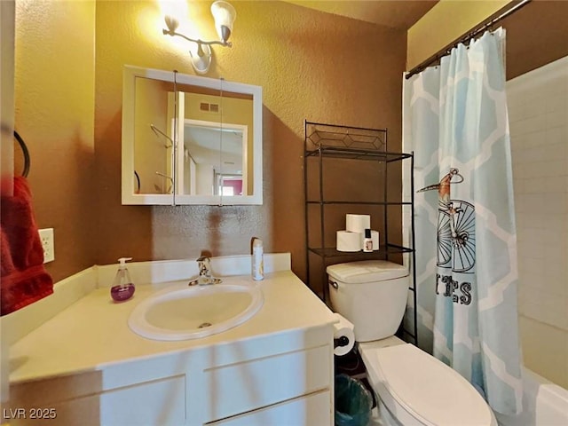 bathroom featuring a textured wall, vanity, and toilet