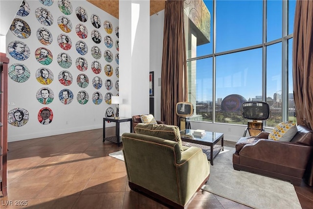 living area with tile patterned flooring, baseboards, a high ceiling, and a view of city