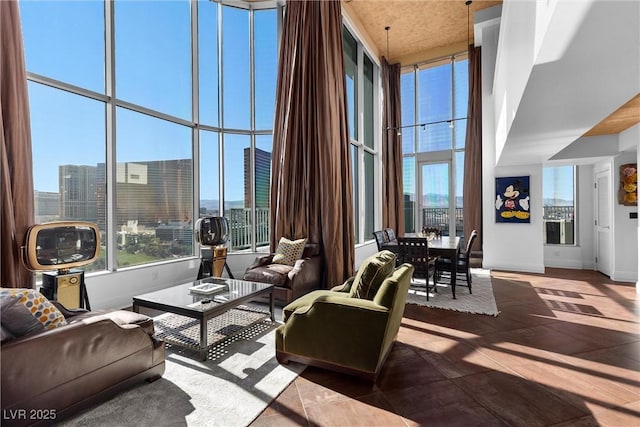 living area with baseboards, a high ceiling, a wealth of natural light, and a city view