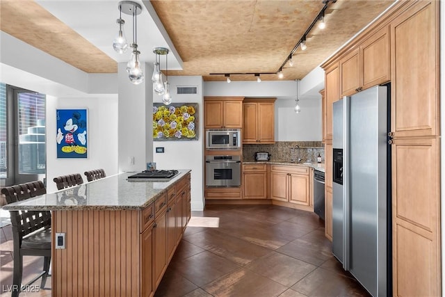 kitchen with a breakfast bar area, stainless steel appliances, backsplash, a sink, and light stone countertops